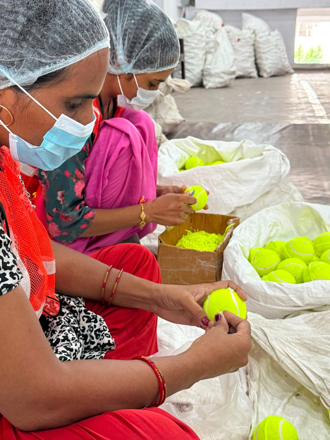 Workers finishing yellow tennis balls before packing